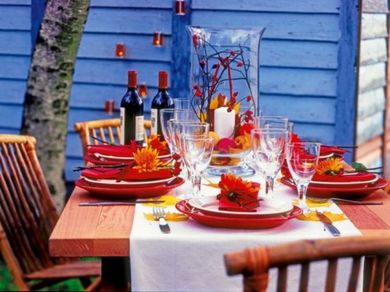 a colorful Thanksgiving tablescape with red porcelain, napkins, blooms, fall leaves and berries is a bright solution