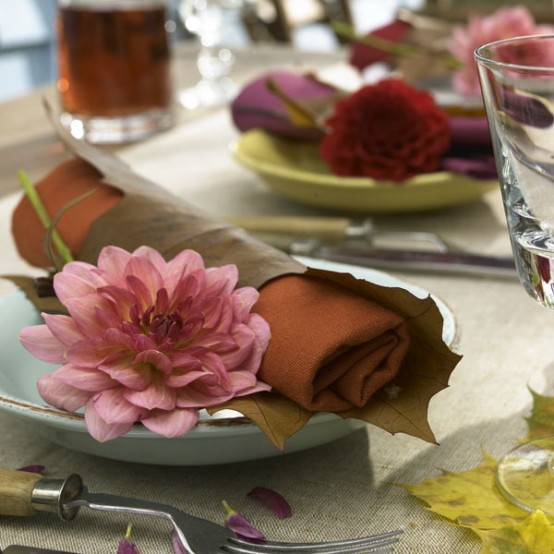 rust napkins covered with fall leaves and with pink blooms will make your tablescape cool and chic, very fall-like