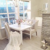 a little and chic dining space with a white table, a refined loveseat and matching chairs, a chic crystal chandelier