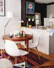 a chic dining zone with a stained round table, white chairs, a white floor lamp and some pretty vases is very modern and cool