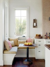 a little cozy dining area with a corner bench with upholstery and pillows, a small table and printed pillows