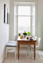 a welcoming Scandinavian dining space with a stained wood table, a white bench with cushions and white chairs, a small gallery wall