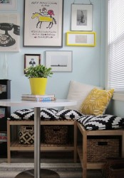 a small and colorful dining nook with a corner bench with colorful cushions, a small round table and a cool and cheerful gallery wall