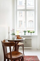 a tiny vintage dining nook with a dark stained table and matching chairs, candles, potted blooms and a printed boho rug