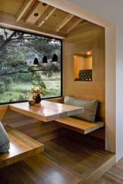 a minimalist dining space with a panoramic view, a built-in table surface and matching seats, pendant lamps and pillows plus lights