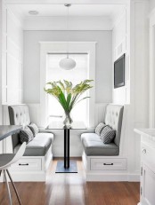 a small modern dining nook with a sleek table and two built-in upholstered benches plus a pendnat lamp is perfect for having meals