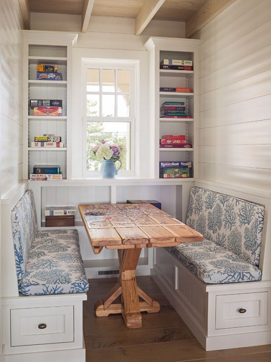 a small rustic dining space with built-in shelves, built-in benches and a stained table, blooms and colorful books