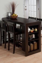 a small dining space with a dark stained kitchen island and table, tall stools, some grass and a candle in a glass candle holder