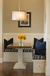 a tiny modern dining zone with a corner bench, a small table, navy pillows and a cool artwork is veyr cozy and cool