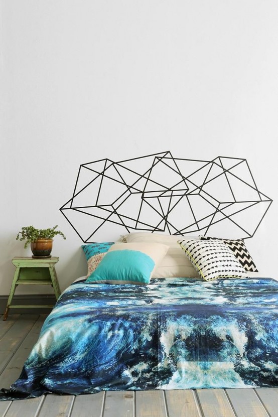 a catchy bedroom with a bed, navy and turquoise watercolor bedding, a black geometric accent on the wall, a green nightstand and plants