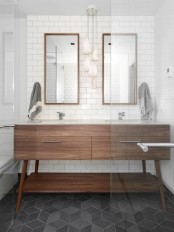an elegant neutral mid-century modern bathroom with subway tiles, a wooden vanity, wooden frame mirrors and catchy geometric tiles on the floor