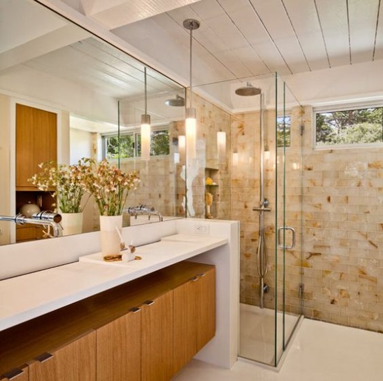 a warming mid-century modern bathroom with earthy tiles, a wooden cabinet under the vanity countertop and large mirrors