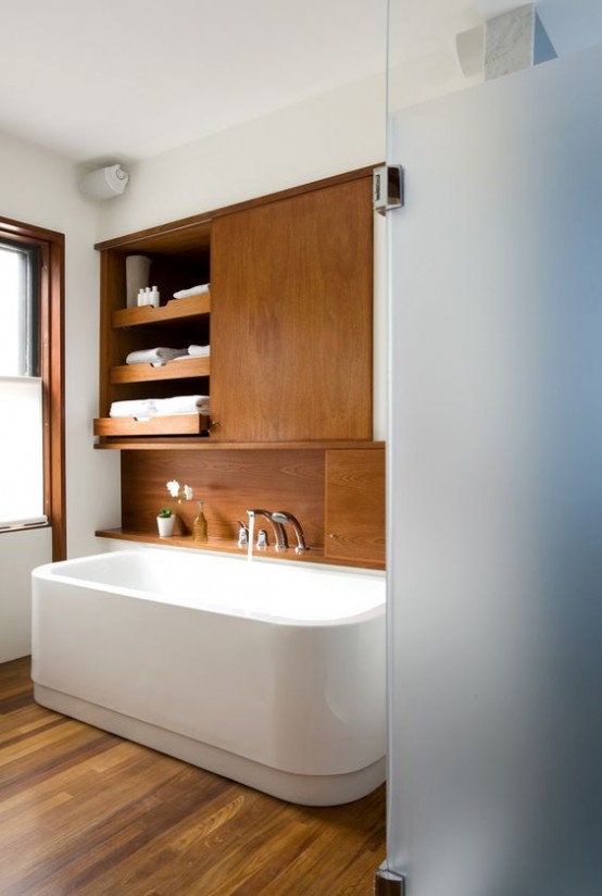 a cozy wood clad mid-century modern bathroom with white walls and appliances plus frosted glass doors is welcoming