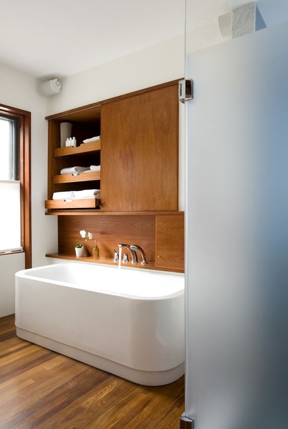 a cozy wood clad mid century modern bathroom with white walls and appliances plus frosted glass doors is welcoming