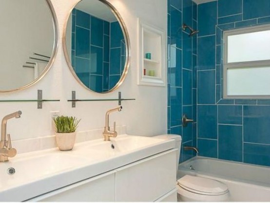 a contrasting blue and white mid-century modenr bathroom with bright tiles in the bathing zone and round lit up mirrors