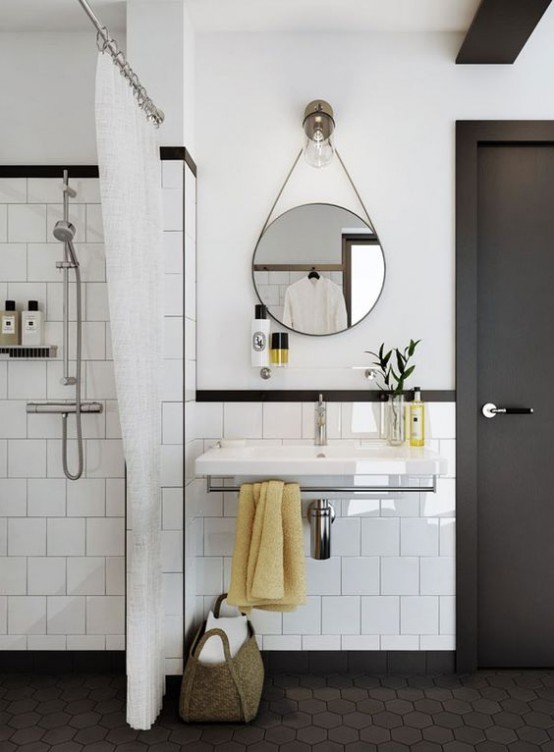 a stylish white and graphite grey mid-century modern bathroom with grey hex tiles on the floor and a round mirror and a floating sink