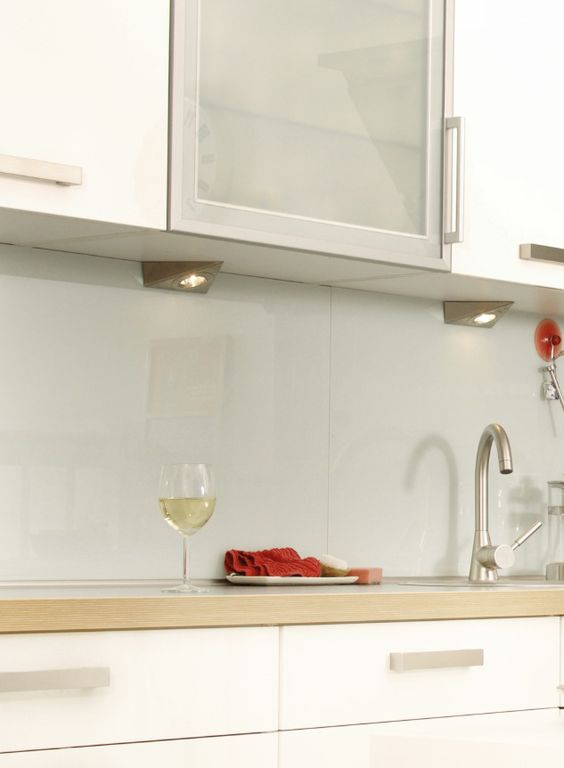 a modern white kitchen with light-stained butcherblock countertops and a grey glass backsplash for a sleeker and more modern look