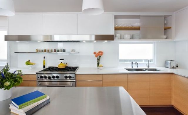a modern light-stained kitchen with white stone countertops and a glossy white glass backsplash is a chic space with much style
