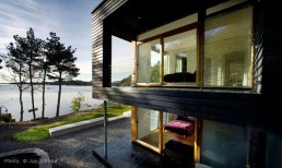 Twofold House In Black Stained Wood With Natural Wood Between The Window Partitions