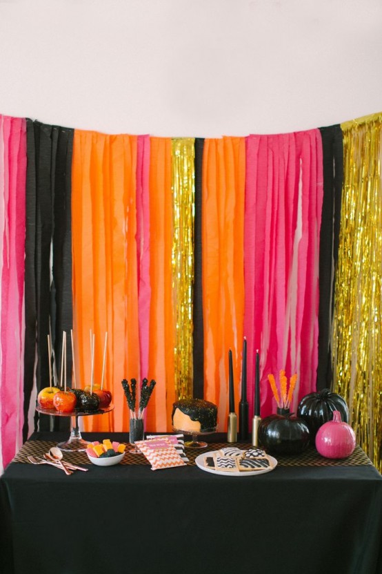 super bright Halloween decor - a bold striped backdrop with glitter touches, a black table with pink and black pumpkins and bold sweets