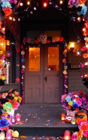 colorful Day of the Dead entrance styling with bold paper blooms, pompoms, spiders, skulls and colorful candle lanterns