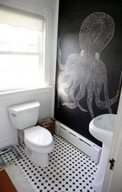 a black and white powder room with a black chalkboard wall, a free-standing sink, a toilet and a printed floor is cool and bold