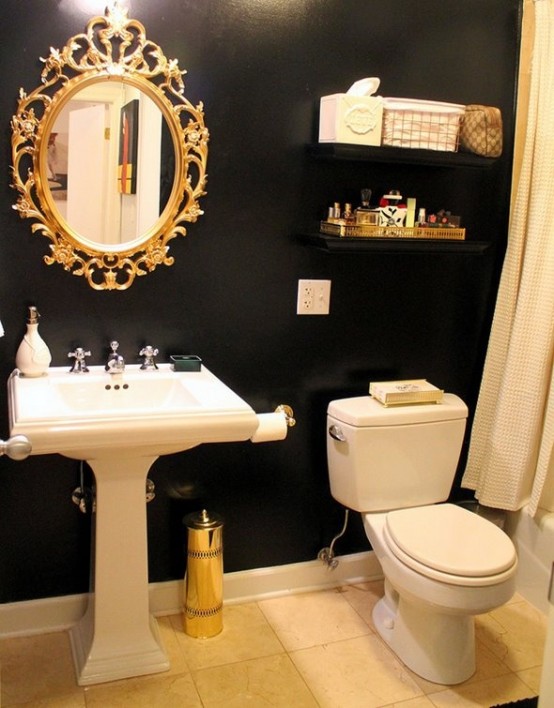 a modern farmhouse bathroom with black chalkboard walls, a pedestal sink, a toilet, a mirror in an ornated frame and some shelves