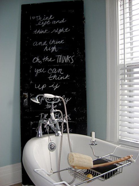 a light blue bathroom with a tub, shutters and a black chalkboard sign is a cool and lovely space to relax in