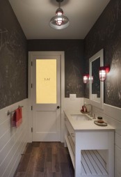 a modern bathroom with color block walls, white tile and chalkboard ones, with a white vanity and a sink, a mirror and some red touches