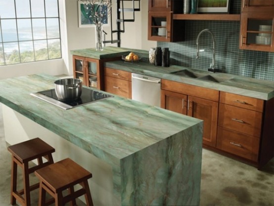 rich stained wooden cabinets with green stone countertops and the same waterfall countertop on the kitchen island