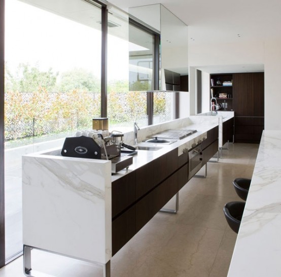 an oversized long kitchen island of dark staiend wood and with a stone countertop includes everything you may need