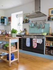 a plywood kitchen island on wheels and with drawers and open shelving for storage contrasts dark and blue furniture