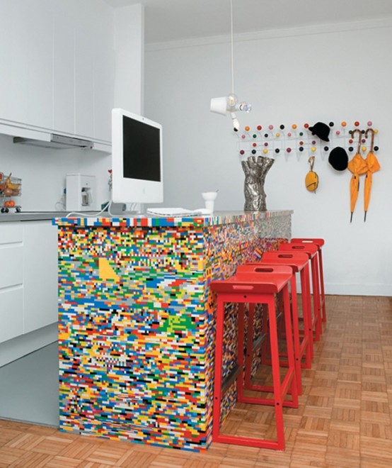 a colorful Lego kitchen island and bright red stools make a statement in the neutral kitchen and spruce it up