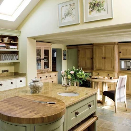 a vintage grey kitchen island witha butcherblock countertop and a round cutting board integrated right into the top