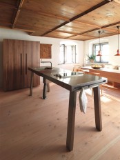 a contemporary wood and metal kitchen island designed as a table to look more lightweight, with a sink and some holders
