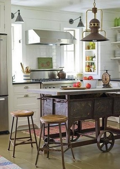 a unique metal vintage wagon on wheels used as a kitchen island, a couple of stools and a pendant lamp