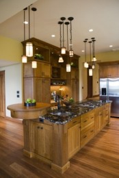 an oversized rustic kitchen island with much storage space, a stone countertop and a round wooden board for cutting or displaying
