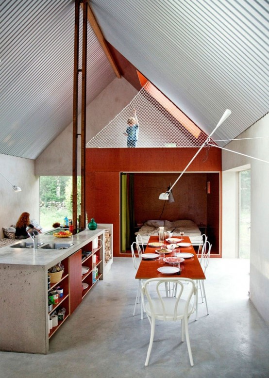 an industrial meets contemporary kitchen island of concrete and redwood, with sinks and much open storage space