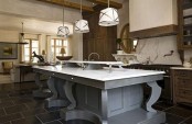 a large vintage grey kitchen island with a white stonr countertop and an additional raised one for storage