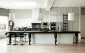 a white kitchen island covered with a large black table to elongate it and make it more functional