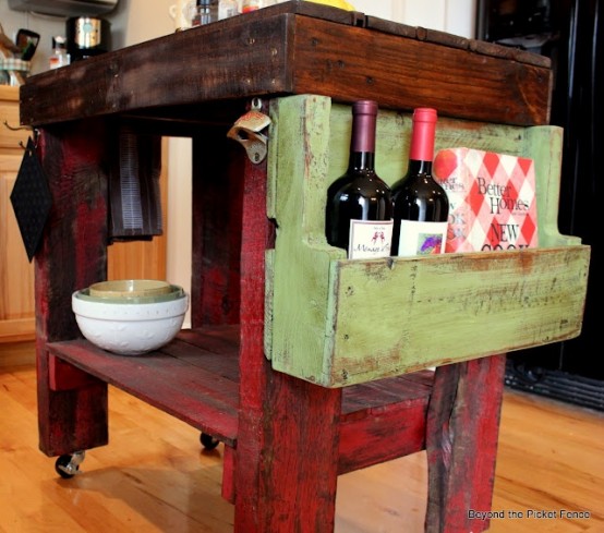 a shabby chic dark stained and red kitchen island on casters plus a green wooden box for storage