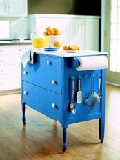 a bright blue vintage dresser on casters with a white countertop and some hangers is a bold and statement idea to rock