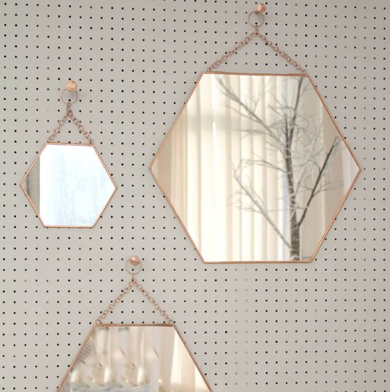 an arrangement of hexagon-shaped mirrors on chain is a lovely gallery wall that will bring shape and interest to the space, and a shiny touch
