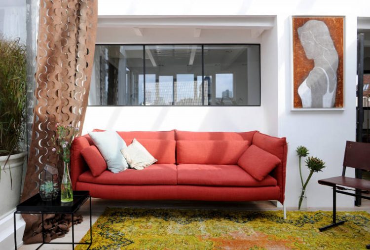 The living room corner is decorated with bright textiles and cool textures