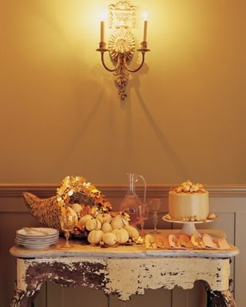 a vintage rustic Thanksgiving dessert table with a woven cornucopia with leaves, mini pumpkins and a refined shabby chic table