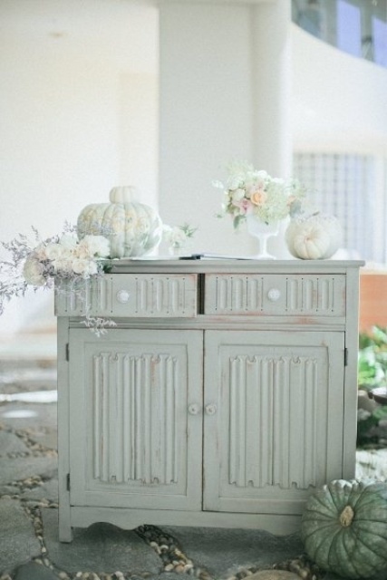 a vintage Thanksgiving table with white blooms, greenery and white pumpkins looks ethereal and very chic
