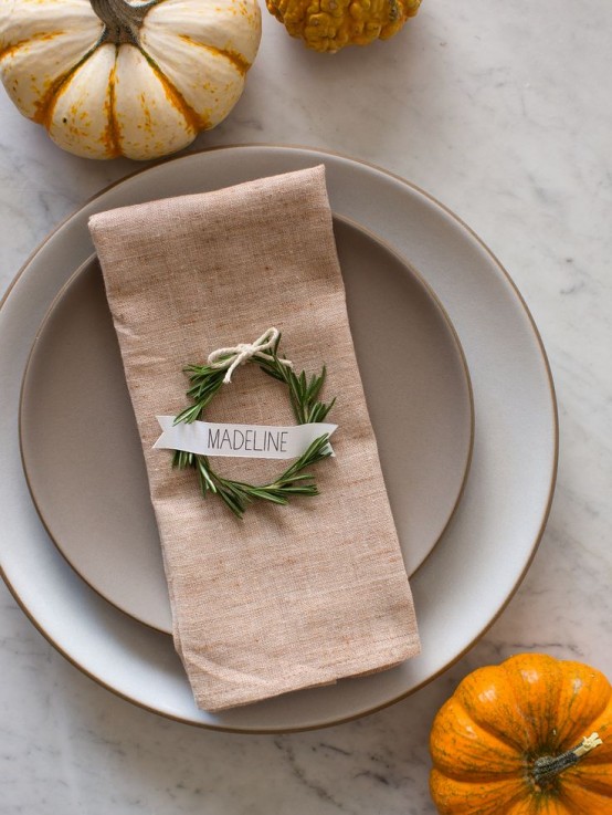 a rustic Thanksgiving table setting with neutral porcelain, mini pumpkins and a wreath with a card is great for Thanksgiving