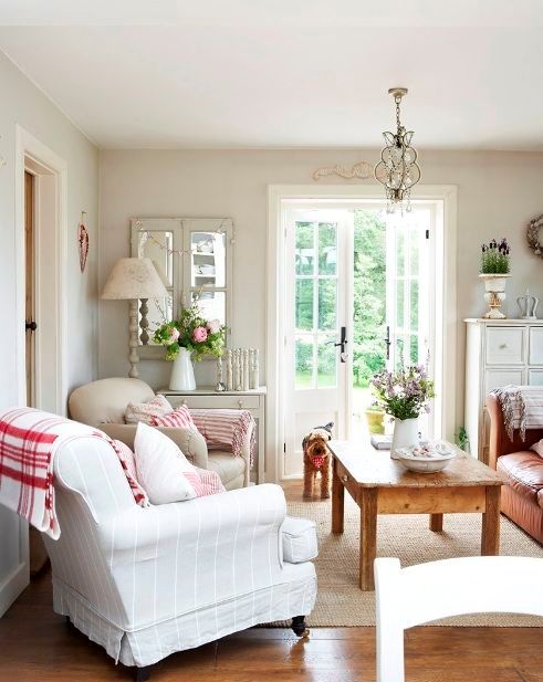 a vintage neutral living room with neutral upholstered furniture, a brown leather sofa, a stained low coffee table, lamps, vintage window frame mirrors