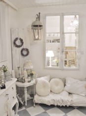 a neutral vintage living room with a white sofa with pillows, a credenza, a side table, a lantern and some wreaths is a lovely space