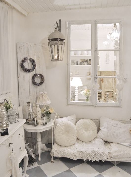 a neutral vintage living room with a white sofa with pillows, a credenza, a side table, a lantern and some wreaths is a lovely space